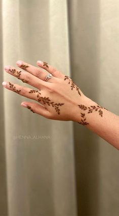 a woman's hand with henna tattoos on her left arm and the fingers