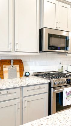 a kitchen with white cabinets and stainless steel appliances, including a stove top oven and microwave