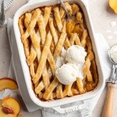 a dish filled with ice cream and peaches on top of a white tablecloth