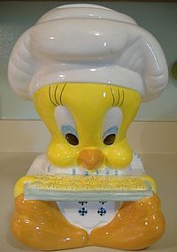 a yellow bird figurine with a chef's hat and apron holding a tray