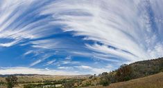 some clouds are in the sky over a field