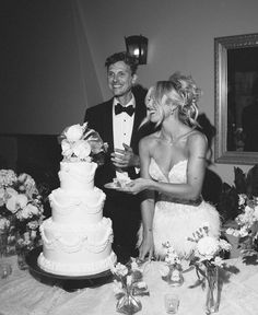 a man and woman standing next to each other in front of a cake