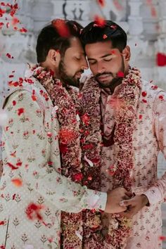 two men standing next to each other in front of red and white confetti