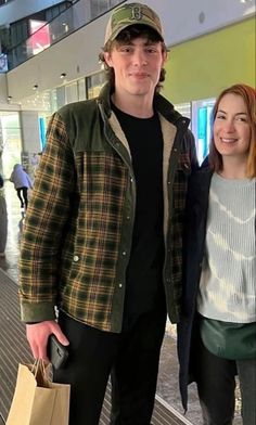 two people standing next to each other holding shopping bags