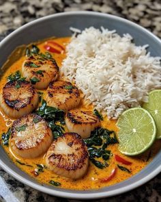 some scallops and rice are in a bowl with limes on the side