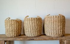 three woven baskets sitting on top of a wooden bench