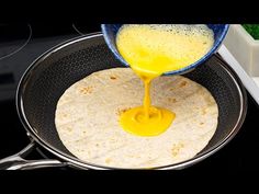 a person pouring orange juice on top of a tortilla in a frying pan