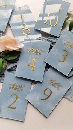 blue and gold table numbers with flowers on the top one is for two, third is for three