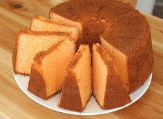 a cake on a white plate with slices cut out and sitting on a wooden table