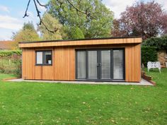 a small wooden building sitting on top of a lush green field next to a tree