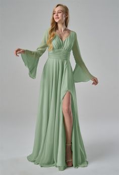 a woman in a long green dress posing for the camera with her hands on her hips