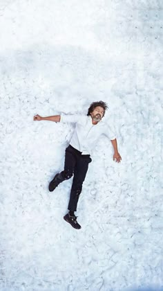 a man is laying in the snow with his arms spread out and eyes wide open