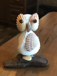 a small figurine sitting on top of a piece of driftwood next to a wooden table