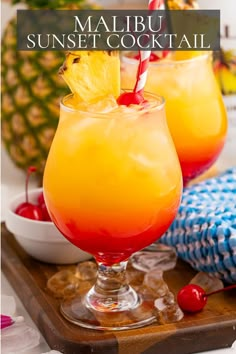 two glasses filled with drinks sitting on top of a wooden tray next to pineapples