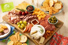 an assortment of cheeses, meats and crackers on a wooden platter