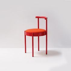 an orange chair sitting on top of a white floor next to a red table and chair