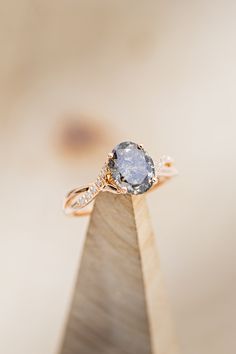 a close up of a ring on top of a piece of wood with a diamond in the middle