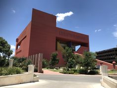 a large red building sitting on the side of a road next to trees and bushes