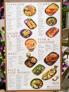 a menu board with different types of food on it and flowers in the back ground