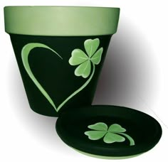 a green pot with shamrocks painted on it and a plate in the shape of a heart