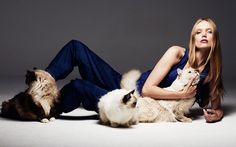 a woman laying on the floor with two cats and one cat is looking up at her