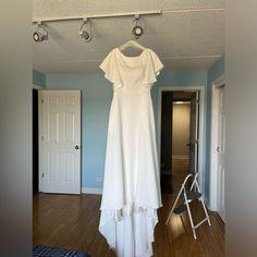 a white dress hanging on a clothes rack in a room with blue walls and wooden floors