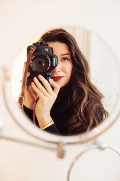 a woman taking a selfie in front of a mirror with a camera on it