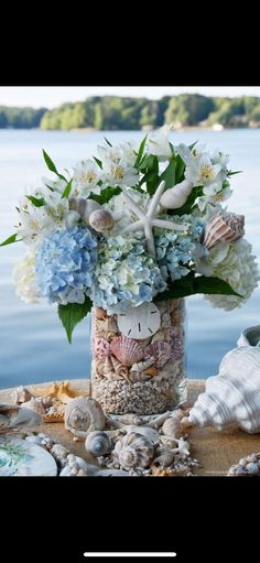 a vase filled with shells and flowers on top of a table