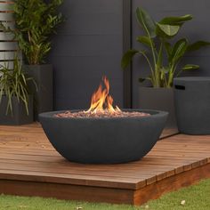 a fire pit sitting on top of a wooden deck next to potted planters