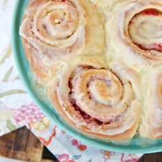 a blue plate topped with cinnamon rolls covered in icing