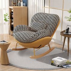 a living room with a rocking chair and books on the floor next to a table