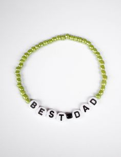 a beaded bracelet with the word best dad written on it in white letters and green beads