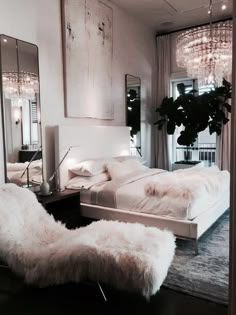 a bedroom with a bed, mirror and chandelier