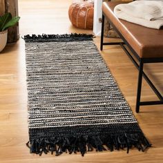 a black and white rug with tassels on the floor next to a chair