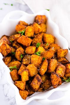 a white bowl filled with fried tofu and garnished with parsley on top