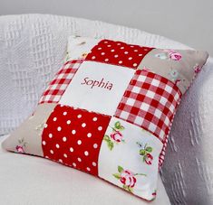 a red and white patchwork pillow with the name sophia on it sitting on a couch