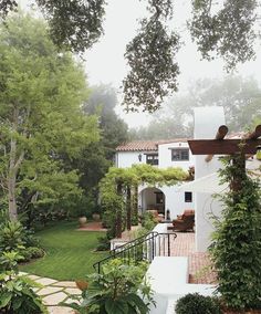 a white house with trees and bushes surrounding it