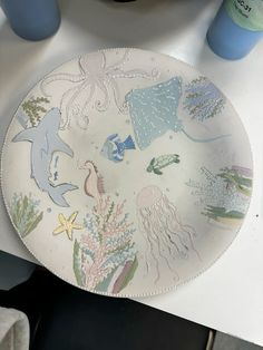 a plate with sea animals on it sitting on a table next to cups and bottles