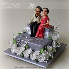 a cake decorated with two people sitting on top of each other and flowers around the edges