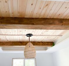 a light fixture hanging from the ceiling in a room with white walls and wood paneling