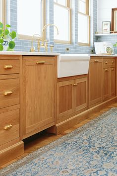 a kitchen with wooden cabinets and a white sink in front of a blue area rug