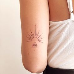 a woman's arm with a small sun tattoo on the back of her left arm