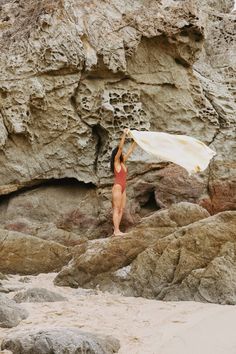 a woman in a red swimsuit holding up a white surfboard