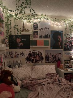 a bedroom with many pictures on the wall and lights strung from the ceiling above it