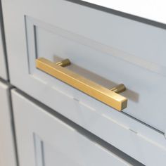 a close up of a drawer handle on a white cabinet with gold handles and knobs