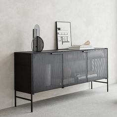 a sideboard with metal mesh doors and drawers in an empty room next to a chair