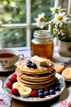 a stack of pancakes with butter, blueberries and raspberries