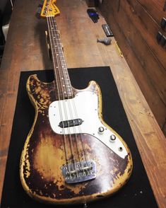 an old bass guitar sitting on top of a wooden floor