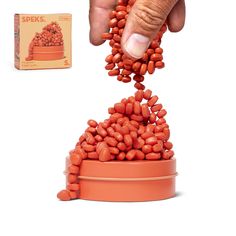 a hand is reaching into a bowl filled with red beans and an orange box next to it