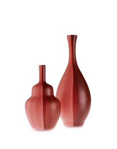 two red vases sitting next to each other on a white surface with no one in it